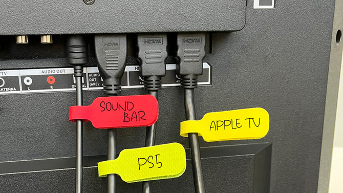 Wrap-It hook-and-loop labels on black cords: from the sound bar (red), PS5 (yellow), Apple TV (yellow).