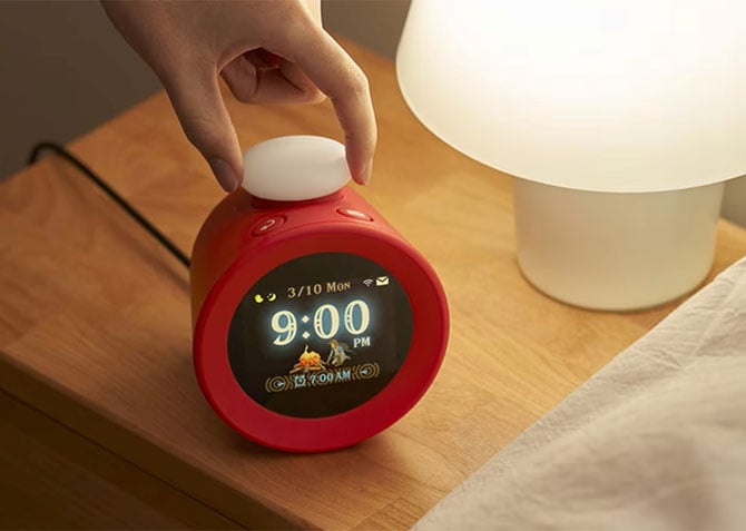 Nintedo's Sound Clock: Alarmo is shown on a nightstand. You can see an alarm set for 7AM with Link sitting next to a fire.