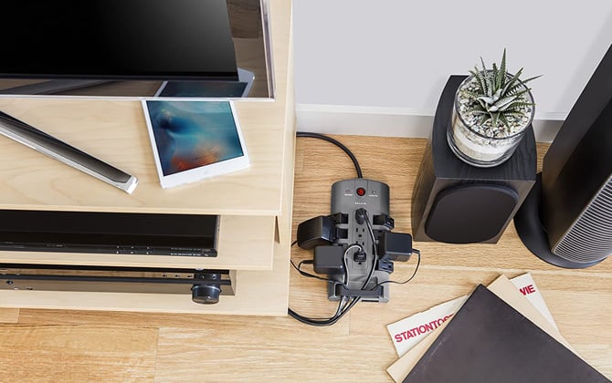 Belkin 12-Outlet Pivot-Plug Surge Protector is shown with audio-video gear and a fan plugged in.