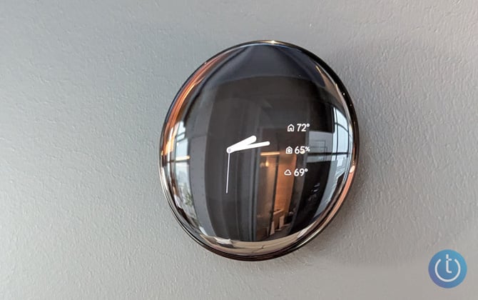 Google Nest Learning Thermostat 4th Gen in obsidian on a wall showing a clock face.