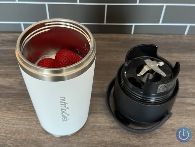 Nutribullet Flip cup is shown with strawberries inside and the blending top is shown next to it with the blades showing.