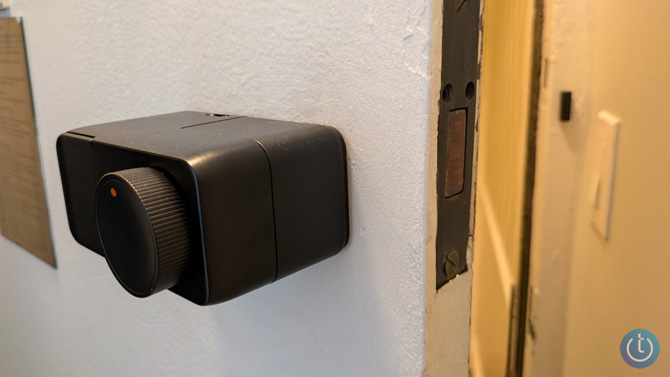 The Switchbot Lock Pro is shown mounted on a door that's open. 