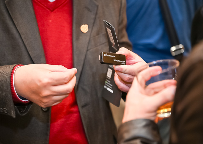 Gausscode GenAI badge is held in a person's hand.