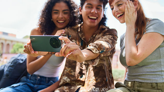 The TCL 60 XE NXTPAPER 5G is shown being help by someon taking a group selfie