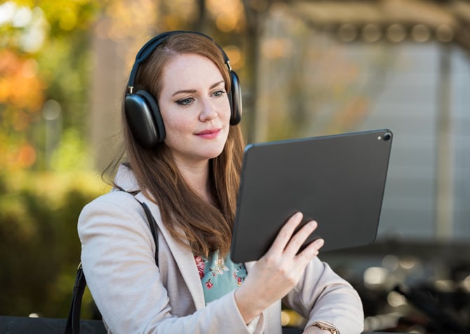 A woman wearing headphones watching a tablet